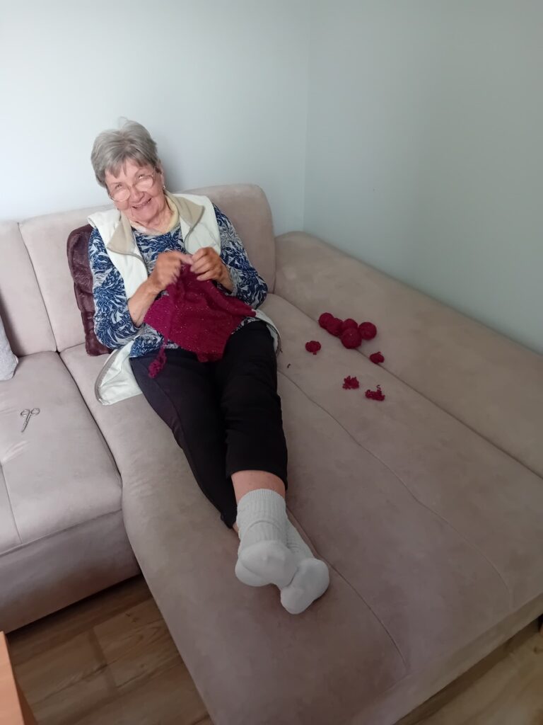 Dôchodkyňa pletúca na gauči v DSS Harmónia
