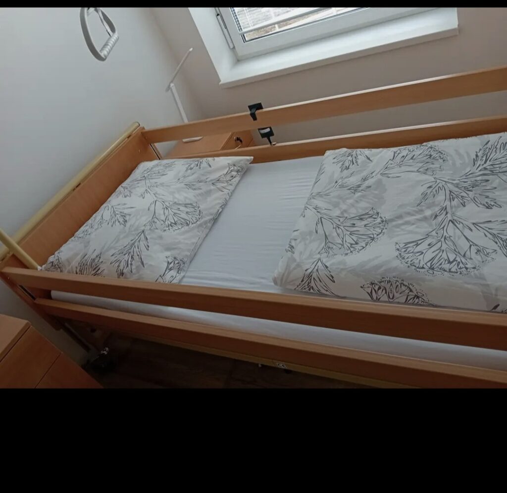 Posteľ s rúčkou, na ktorej je vankúš a perina