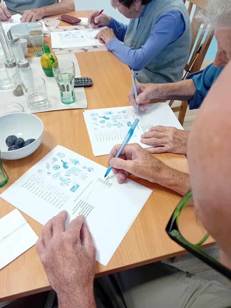 Seniori vypĺňajú pracovné listy počas tréningu pamäti pri spoločnom stole