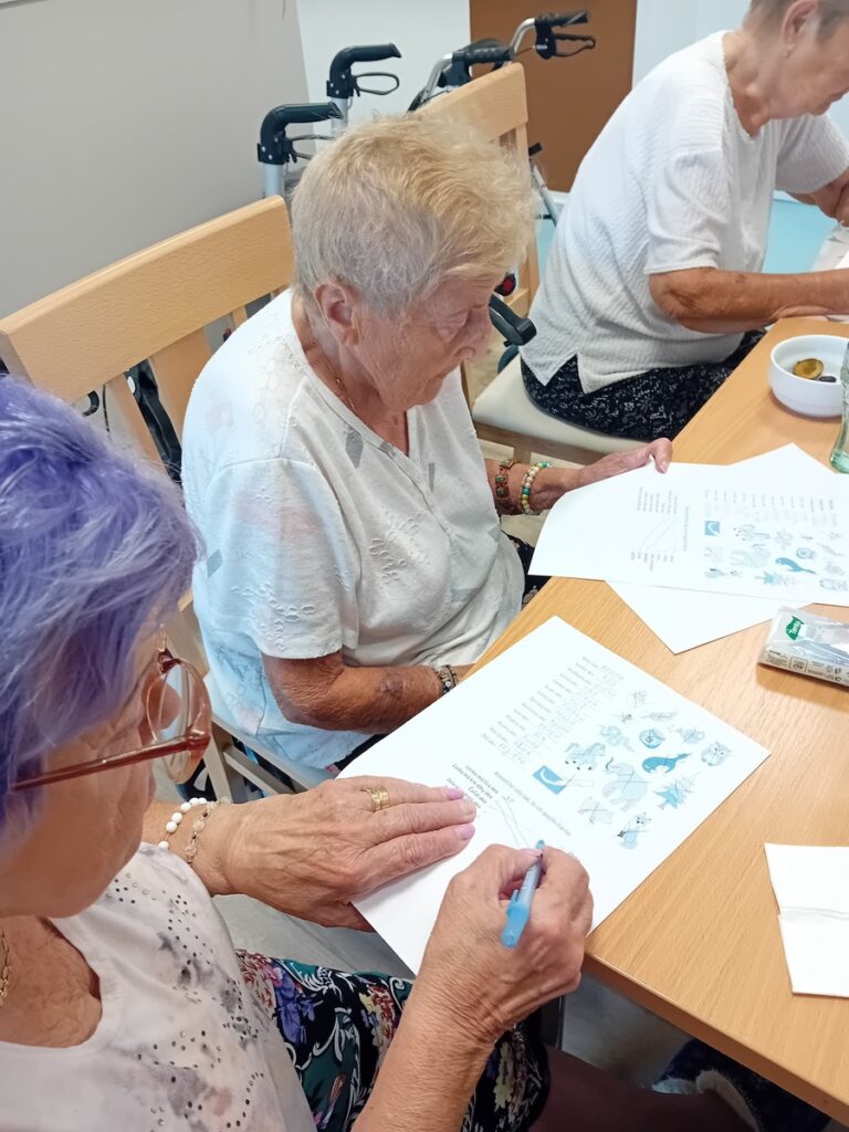 Seniorka sa sústredí na riešenie úloh z pracovného listu počas aktivít v Harmónii