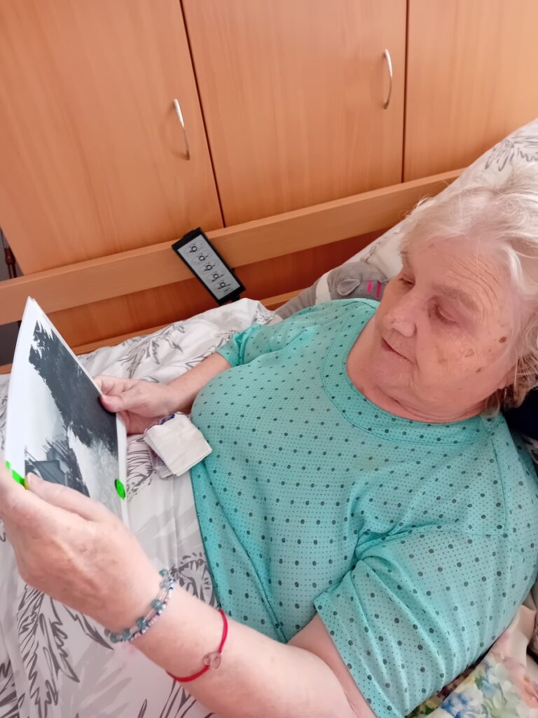 Seniorka si prezerá historickú fotografiu počas individuálnej spomienkovej aktivity