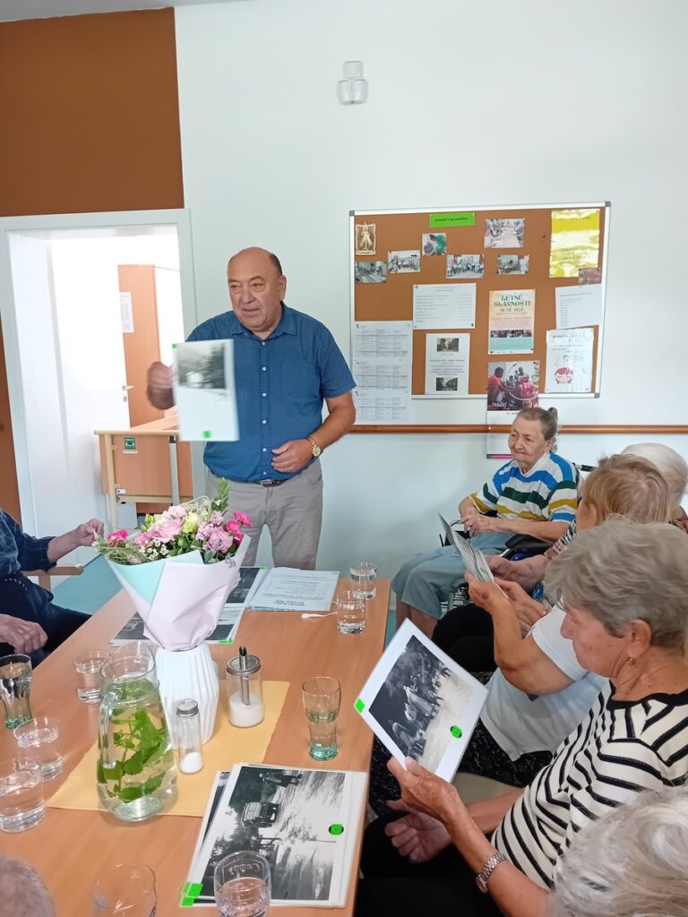Diskusia seniorov nad starými fotografiami počas spomienkovej aktivity v Harmónii
