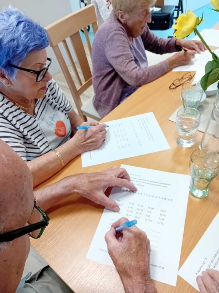 Seniori vypĺňajú pracovné listy počas tréningu pamäti v zariadení Harmónia