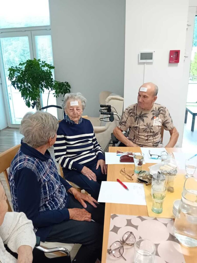 Skupinové cvičenie pamäti seniorov pri stole v zariadení Harmónia
