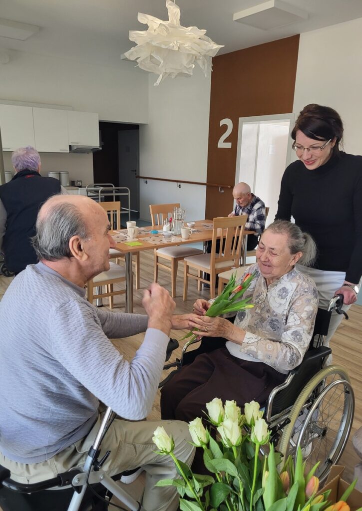 Odovzdanie kvetov klientke v zariadení Harmónia počas spoločenského podujatia