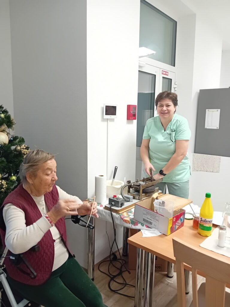 Personál Harmónie s dôchodkyňou pri tvorbe oblátok